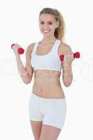 Young attractive woman smiling while lifting red weights