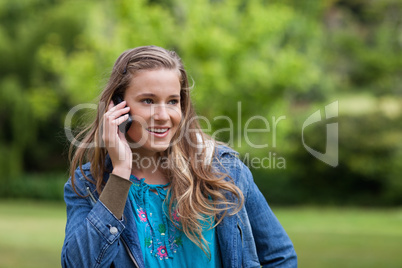 Smiling teenage girl looking towards the side while using her ce