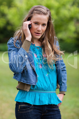 Teenage girl using her mobile phone while looking at the camera