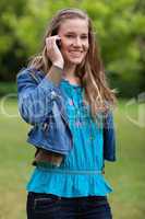 Young smiling and relaxed girl talking on the phone while standi