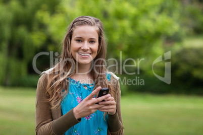 Smiling teenage using her cellphone while sending a text