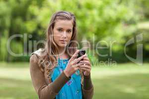 Teenage girl sending a text while looking at the camera