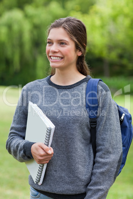 Young happy woman showing a beaming smile while holding a notebo
