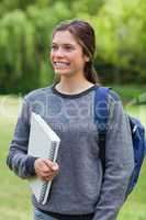Young happy woman showing a beaming smile while holding a notebo