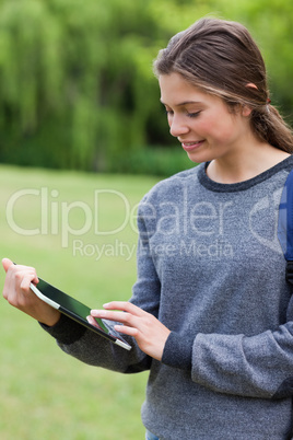 Young smiling woman touching her tablet pc while standing uprigh