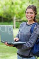 Smiling young girl holding her laptop while looking at the camer