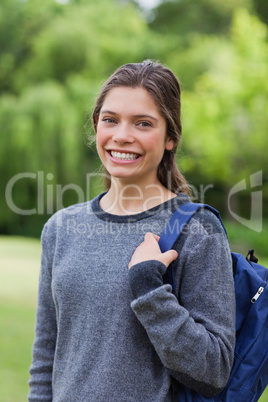 Young girl standing up with hair tied while carrying her backpac