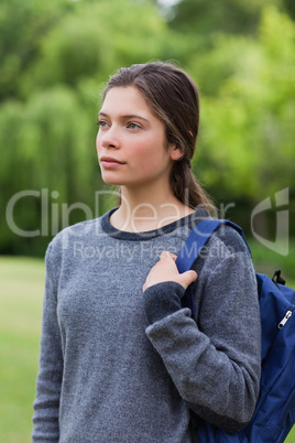 Thoughtful young girl standing in the countryside while carrying