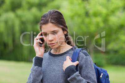 Thoughtful young girl using her mobile phone while carrying her