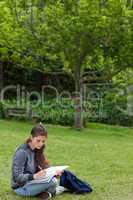 Young serious girl doing her homework while sitting down in a pa