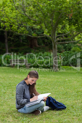 Smiling young girl writing on her notebook while sitting on the