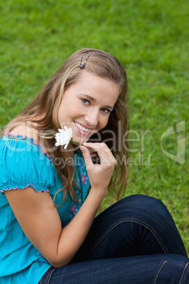 Smiling young girl holding a flower next to her face