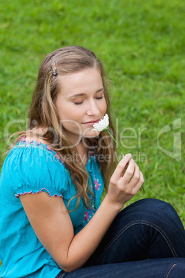 Young attractive woman smelling a flower while closing her eyes