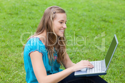Young attractive girl looking at her laptop while sitting in the
