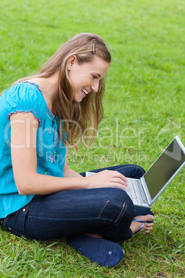 Young smiling woman sitting cross-legged in the countryside with