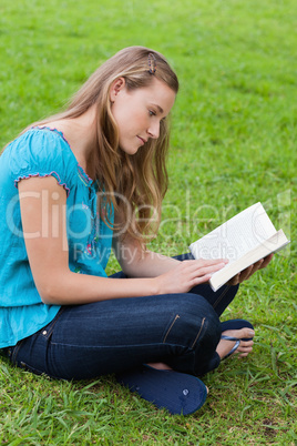 Serious young girl reading a book while sitting in a park