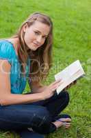 Young relaxed girl reading a book while sitting in the countrysi