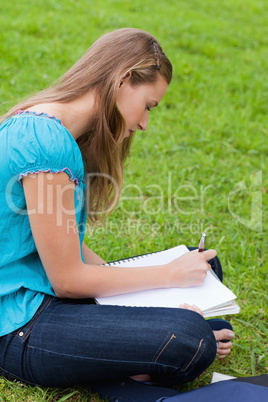 Serious young girl writing on her notebook while sitting on the