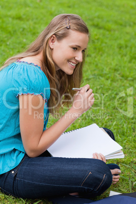 Young smiling girl looking towards the side while writing on her