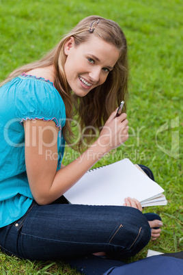 Young smiling student holding her pen while looking at the camer