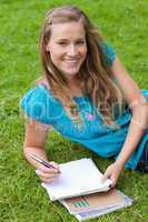 Young smiling girl looking at the camera while lying on the gras