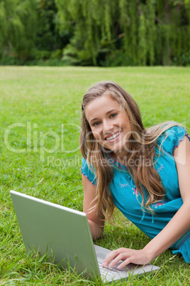 Young girl looking at the camera while using her laptop and smil