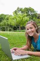 Smiling teenager looking at the camera while using her laptop