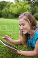 Young smiling woman using her tablet computer while lying in a p