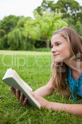 Thoughtful young woman holding a book while looking away