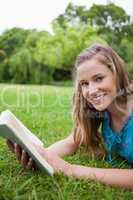 Smiling teenage girl holding a book in a parkland while looking