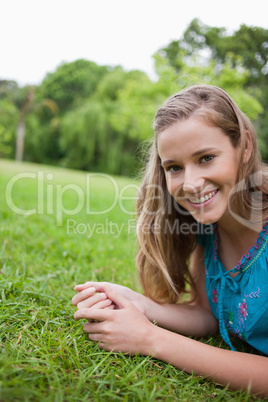 Young smiling woman lying on the grass in a public garden