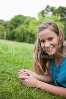 Young smiling woman lying on the grass in a public garden