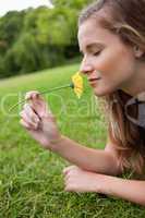 Young calm woman closing her eyes while smelling a yellow flower