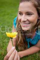 Young smiling girl looking away while lying on the grass and hol