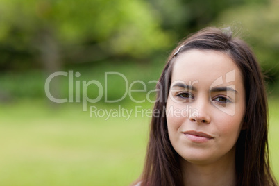 Young calm woman standing upright in a parkland