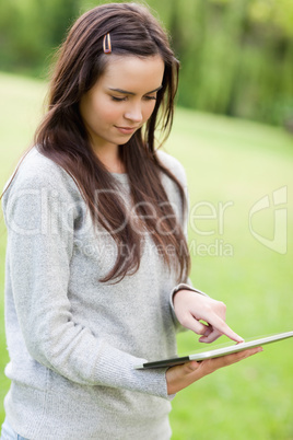 Serious young woman standing up while using her tablet computer