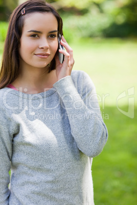 Young serious woman calling with her cellphone while standing in