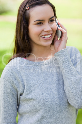 Young girl using her mobile phone while standing in a park