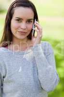 Peaceful young woman using her mobile phone while standing in a