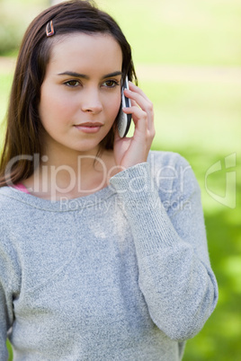 Serious young woman using her cellphone while standing in the co