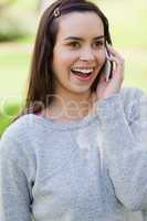 Surprised young woman talking on the phone while standing in a p