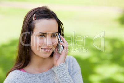 Young relaxed girl talking on the phone while standing in the co
