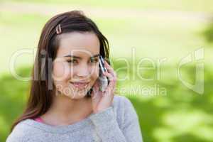 Young relaxed girl talking on the phone while standing in the co