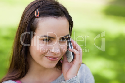 Young relaxed girl talking on the phone in a park