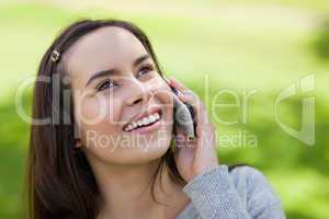 Young smiling woman looking up while talking on the phone