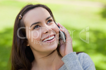 Young smiling woman talking on the phone while looking up