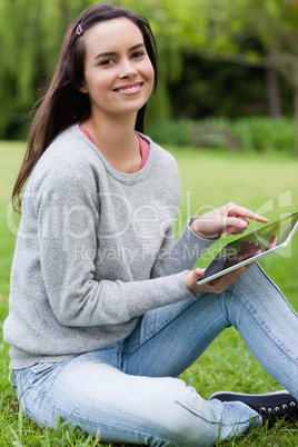 Young smiling woman looking at the camera while holding her tabl
