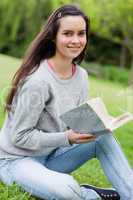 Young smiling woman holding her book while looking at the camera