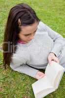 Young woman reading a book while lying on the grass