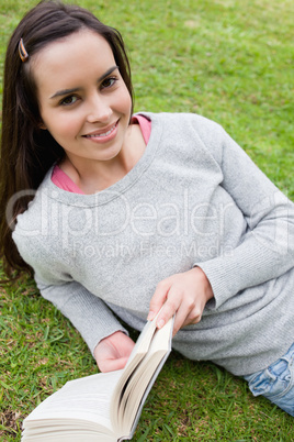 Young smiling girl looking at the camera while holding a book